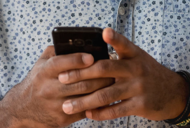 African,Guy,Holds,Phone,Using,Apps,,Take,Break,During,Workday - Consultant Connect