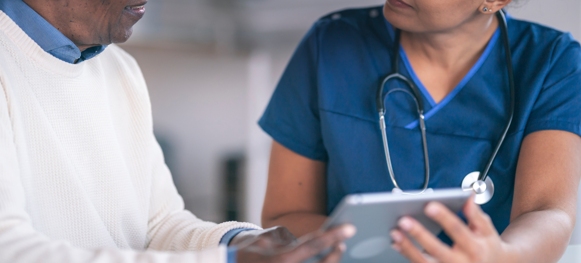 female clinician using tablet speaks with male patient